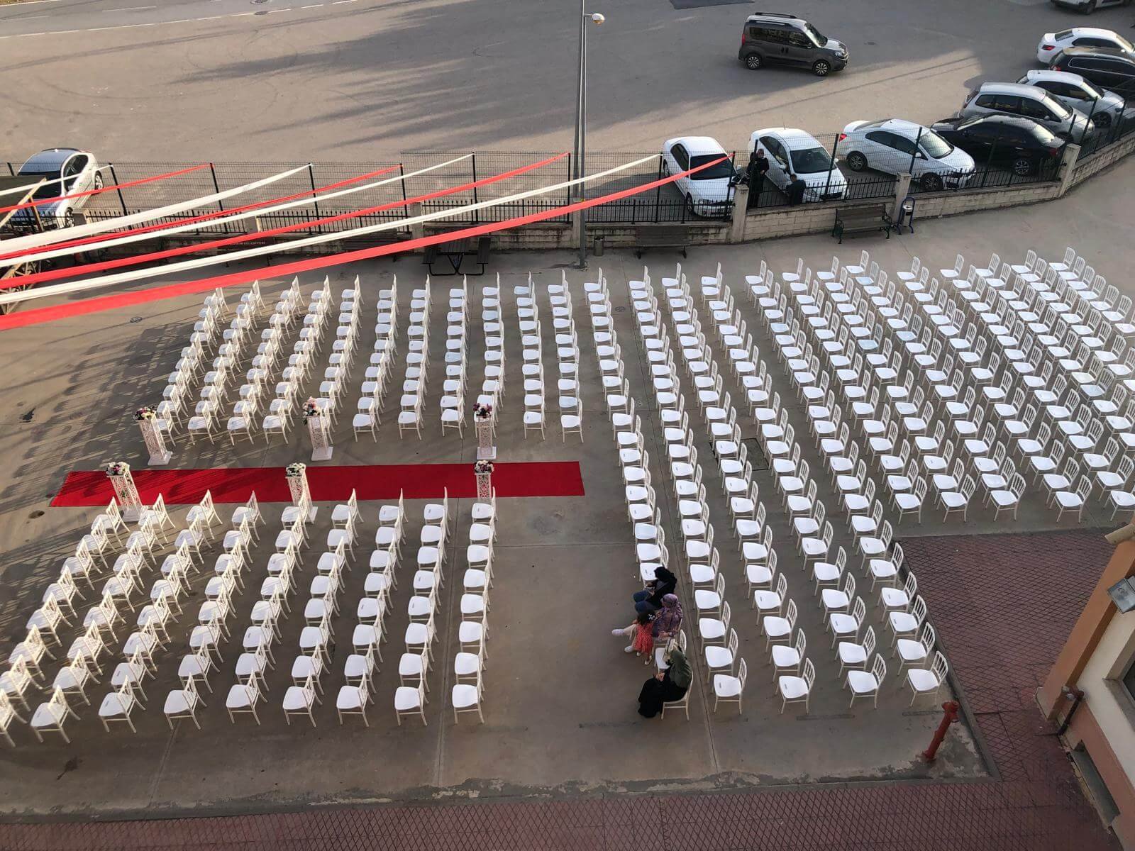 Mezuniyet kepi atma töreni sırasında, DJ performansının eşlik ettiği coşkulu gençlerin ve ailelerin fotoğraf çekimi için ışıklandırılmış alanda bir araya gelişi.