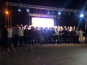 Bursa'da Zeynepce Ajans tarafından düzenlenen görkemli bir açılış veya kurumsal etkinlikte, sahne önünde kurdele kesimi yapan kalabalık bir katılımcı grubu. Gece çekilmiş, ışıklandırmalı sahne ve konfeti detayları mevcut.